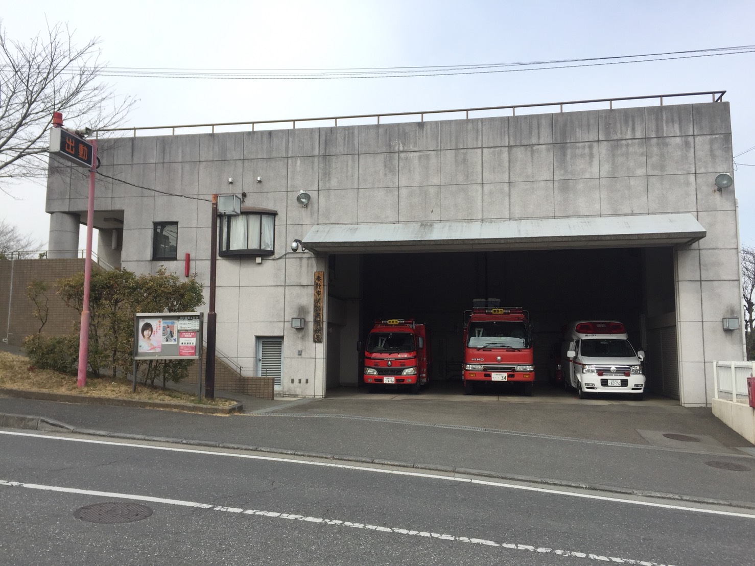 道路に面したコンクリート造りの平坦な外観を持ち、車庫に赤色の消防車2台と白色の救急車1台が駐車している消防署南分署の外観写真