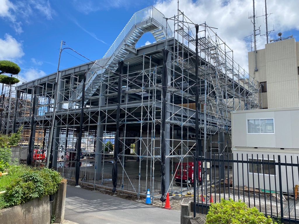 足場とむき出しの鉄骨が組み合わさった、建設中の消防署の写真