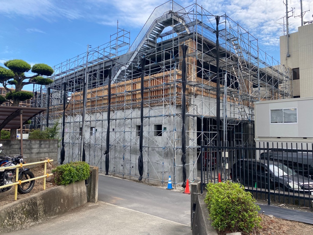 鉄骨の骨組みがむき出しで、足場が組まれ、外階段が設置されている、建設中の消防署の外観の写真