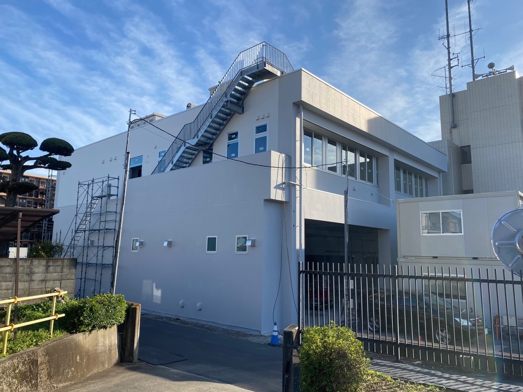 足場が組まれている工事中の白い建物の外観を写した写真