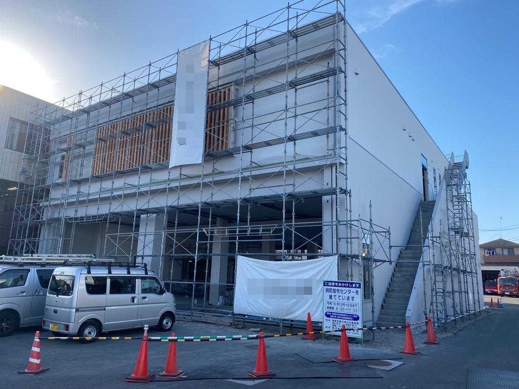 鉄骨の足場が組まれ、白いシートがかけられた建物の外壁工事の様子を写した写真