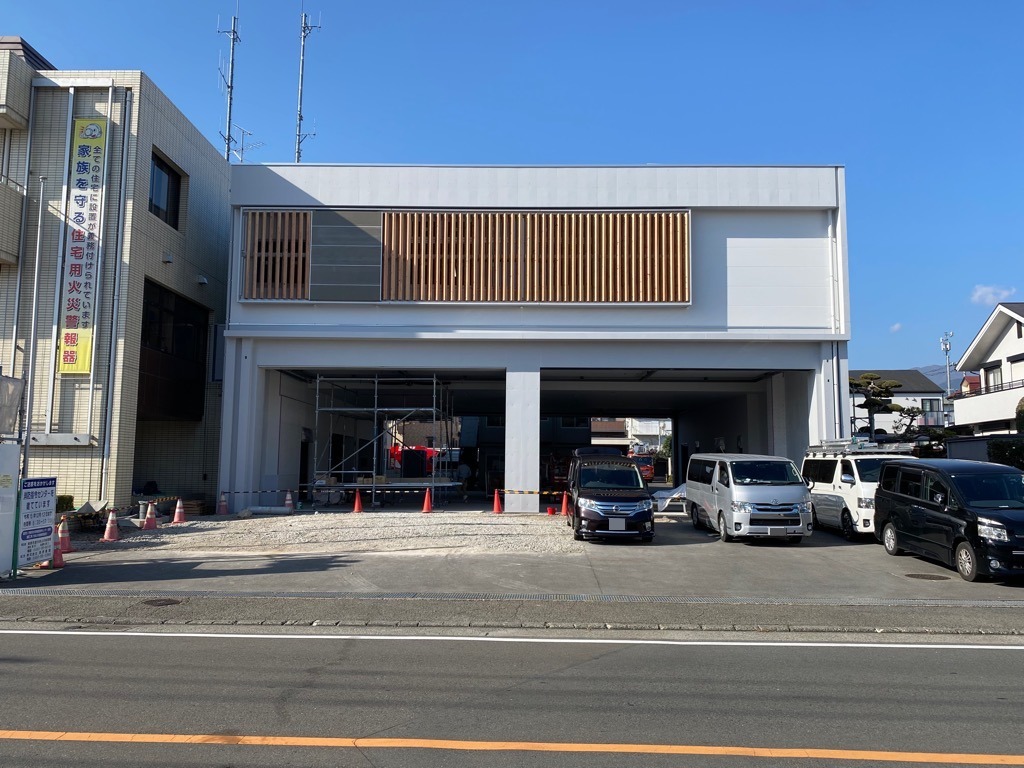 建築現場の足場と、工事用の赤いコーンが並べられており、複数の乗用車が駐車している建設中の消防署の写真