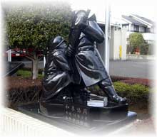 救助隊員が倒れている隊員を抱きかかえて助け起こしている緊迫した瞬間を捉えた、台座に乗せられた「和衷協同」防人像の写真