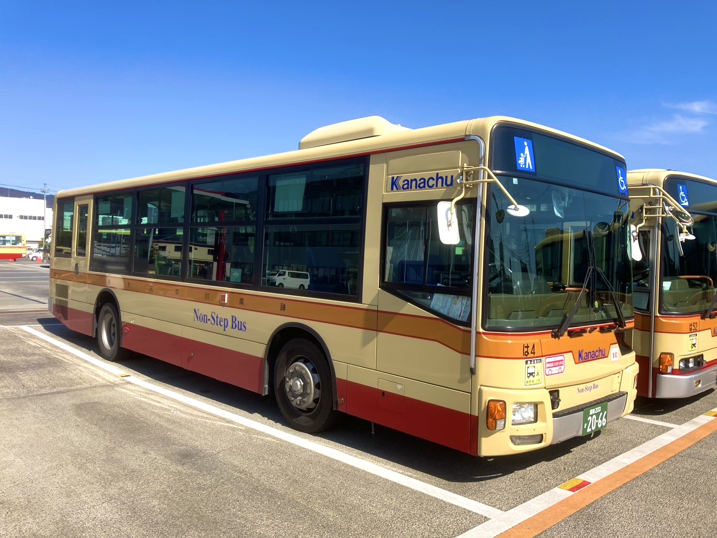 明るいベージュと赤色のツートンカラーの車体に「Kanachu」と「Non-Step Bus」の文字が描かれ、車椅子マークが確認できる路線バスが駐車場に停車している様子の写真