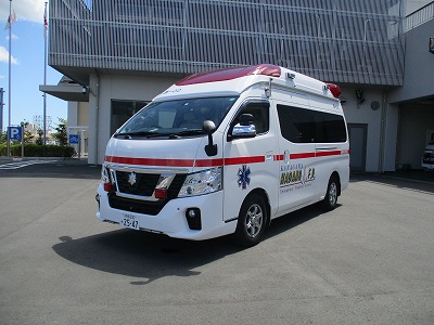 白い車体に赤いラインが入った救急車が建物の前に斜めに停車しており、側面には「KANAGAWA HADANO F.D. Emergency Medical Service」と書かれ、青い救急マークと赤色灯が装備された、消防署西分署の救急車の写真