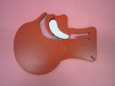 ピンク色の背景に置かれた、人体の頭部断面を模したオレンジ色のプレート型模型で、白い舌が喉の奥を塞いでいる気道閉塞の状態を示している救急講習用気道確保モデルの写真