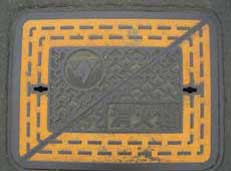 黒っぽい長方形のマンホール蓋で、蓋の外周と内側の長方形の枠が、黄色の破線と実線で強調されている消火栓の写真