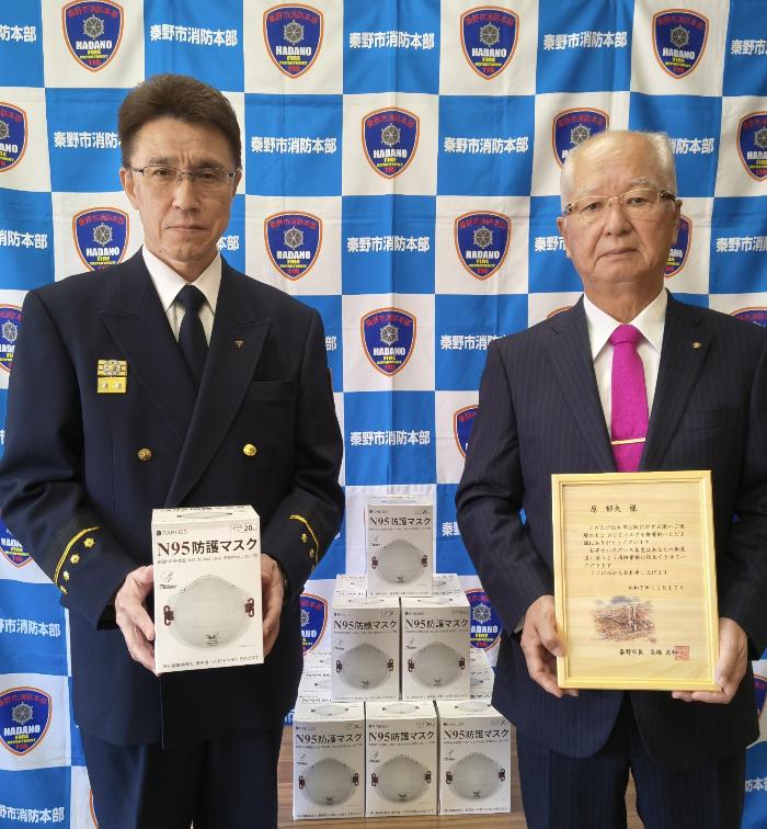 秦野市消防長がN95マスクを持ち、寄贈者が感謝状を持って記念撮影している写真