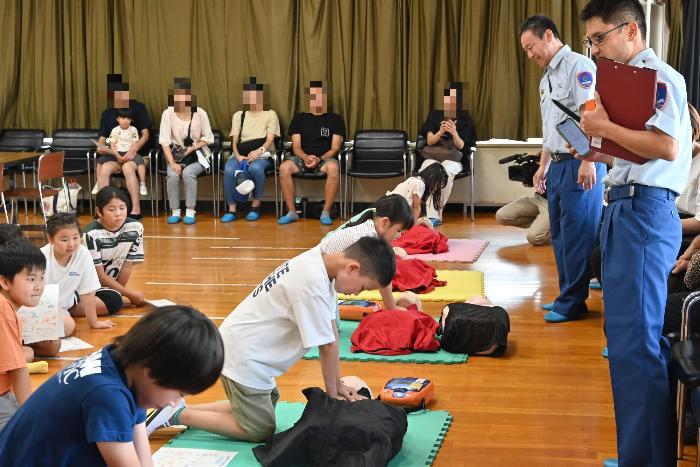 子供たちが一列になり、胸骨圧迫とAEDの実施体験をしている