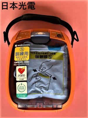 オレンジ色のAEDで、日本光電、訓練用救命には使用できませんと書かれている。
