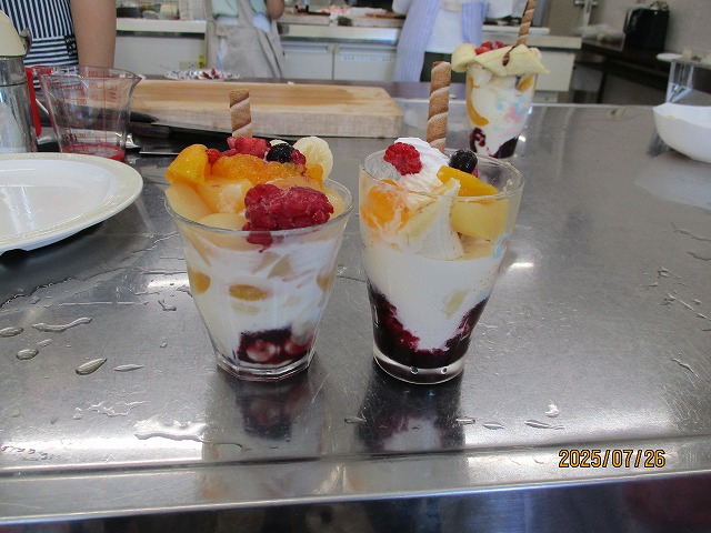 透明なグラスにアイスクリームやフルーツ、チョコレートを層にして盛り付け、お菓子を添えた子供たちの手作りパフェが二つ並んでいる写真