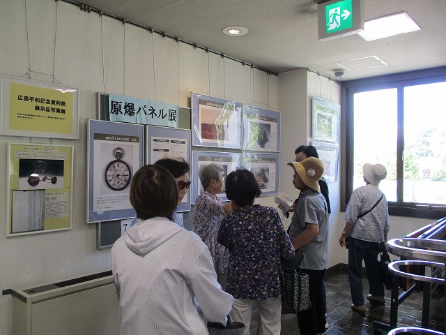 複数の方が「原爆パネル展」の内容について語り合いながら展示を見ていている写真