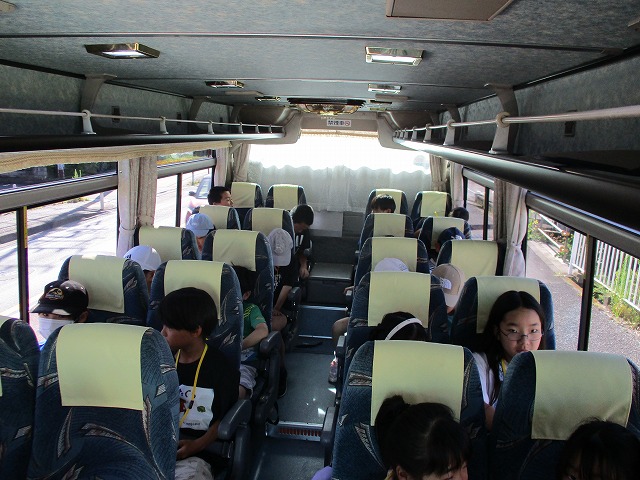 子供たちが観光バスの座席に座っている様子を、前方から撮影した写真