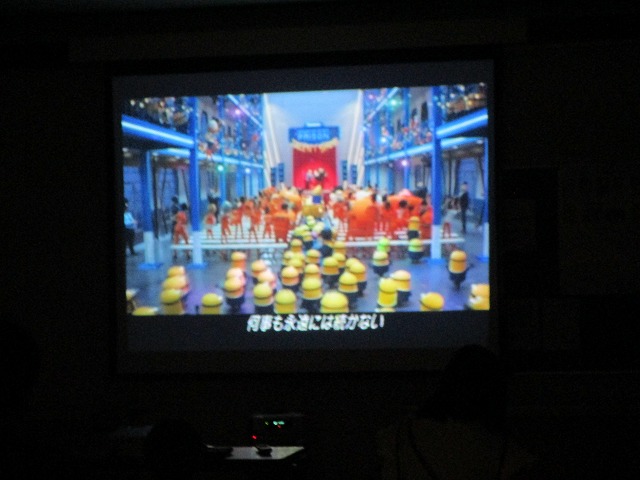 スクリーンに「ミニオンズ」のキャラクターたちが並んで映っており、映画のワンシーンに字幕が表示されている映写画面の拡大の写真