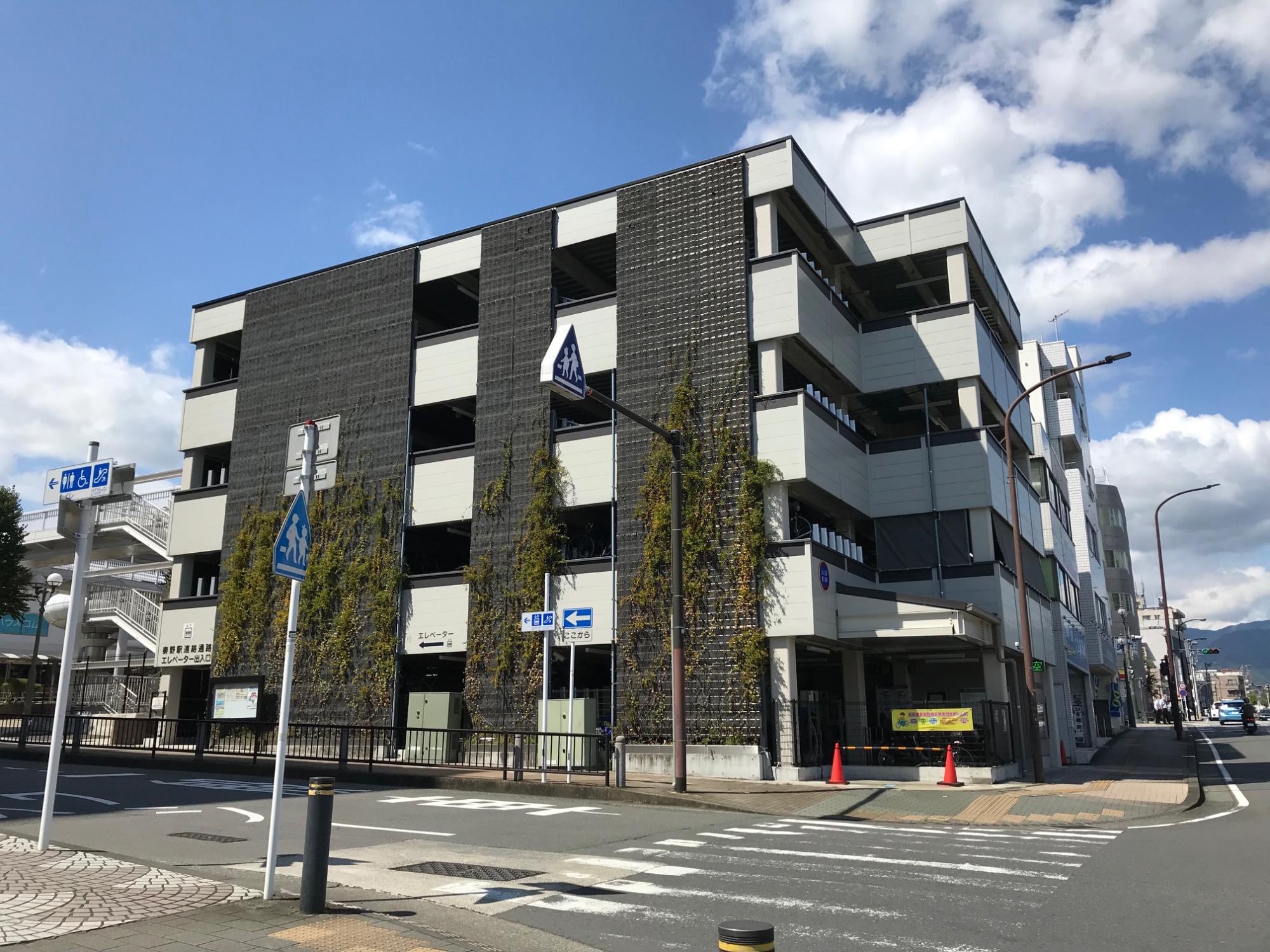 外壁に植物が植えられた黒いパネルが設置された多層階の立体駐車場の写真