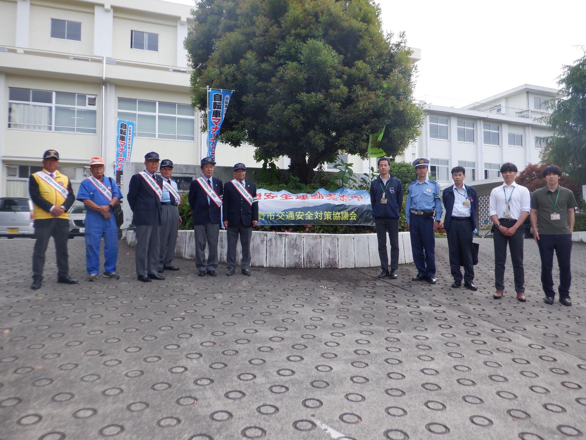 交通安全対策協議会のイベントで、警察官や市の職員、地域のボランティアといった様々な立場の男性たちが集まり集合写真を撮っている様子の写真