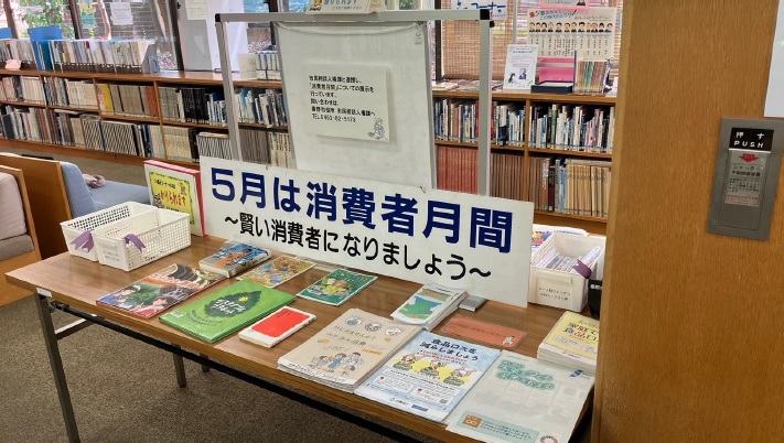 図書館内に置かれた長机に「5月は消費者月間 賢い消費者になりましょう」と書かれた案内板が立てられ、消費生活関連書籍やパンフレットが並べられている写真