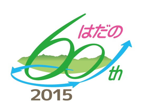 緑色で「60」をかたどり、その下に緑の山並みのイラスト、上部にピンク色で「はだの」の文字、下部に「2015」の数字、周囲を矢印が囲む「はだの60th 2015」のロゴマークイラスト