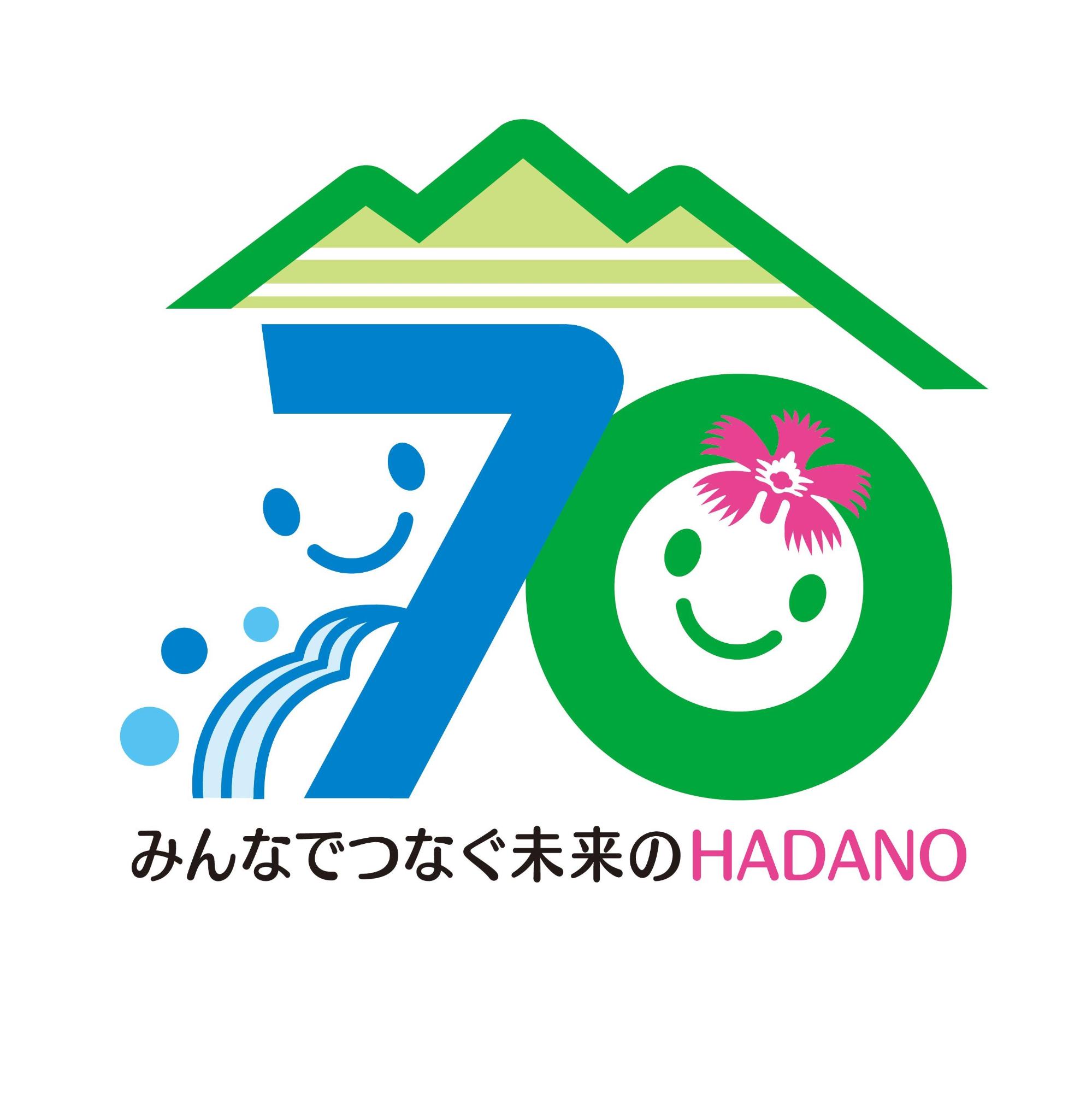 丹沢連峰を背景に、笑顔のキャラクターと市の花ナデシコ、流水のイラストが「70」という数字と組み合わされて描かれており、「みんなでつなぐ未来のHADANO」という文字が添えられたロゴマークのイラスト