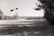 木々が影を落とす広い校庭の先に校舎が見える東中学校のモノクロ写真