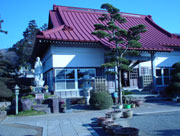 石灯籠や石像、手入れされた植栽が並ぶ庭の後ろに赤い屋根建物が建っている円通寺の写真