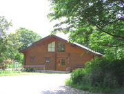 木々に囲まれて、ロッジ風の建物が広場に面して建っているくずはの家の屋外写真