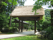 樹木が茂る庭園内に、茅葺き屋根の重厚な門が建ち、その奥に別の建物が見える命徳寺周辺の写真