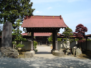 大きな石碑の後ろに、赤い屋根の重厚な門が建っている、太岳院の写真