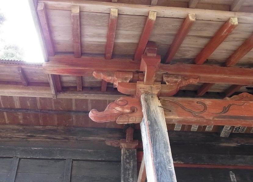 柱と交差する屋根下の朱色の梁に装飾が施された、水引虹梁木鼻の写真