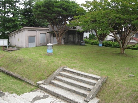 コンクリート製の建物や階段、そして灯籠のようなものが設置されている、広々とした芝生が広がる公園の一角を写した写真