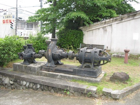 台座の上に、まるでオブジェのように置かれている黒い鋳鉄製の重厚な機械を写した写真