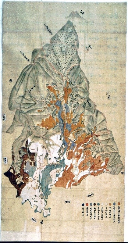色付けされた山や川、村の様子が描かれた古地図で、右下には凡例と文字が記されている縦長の山論裁許絵図