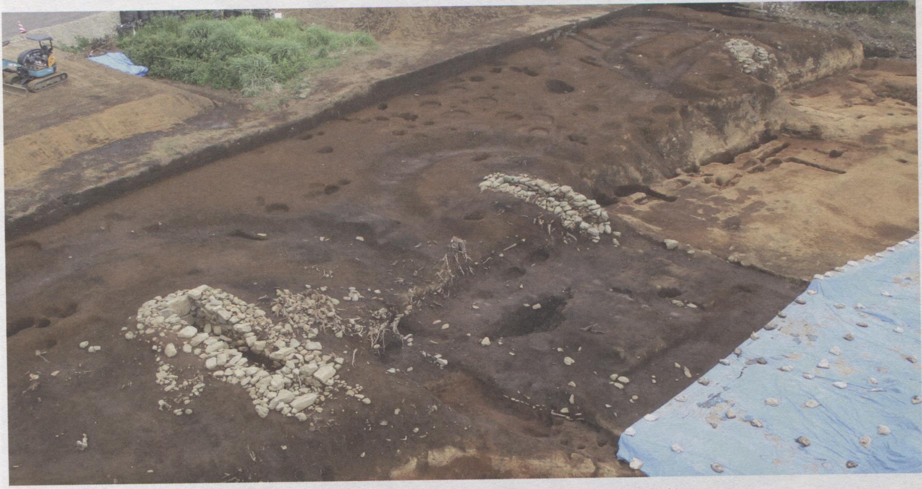 複数の穴と石組みの遺構が地表に露出した、広大な菩提横手遺跡を上空から撮影した写真