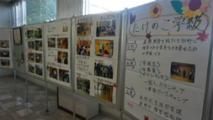 窓の前に並んだ複数の展示パネルに、たくさんの活動の様子の写真が説明付きで貼りだされている展示の様子の写真