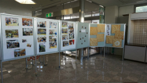 入り口横のスペースに並んだ複数の展示パネルに、たくさんの写真と制作物が展示されている写真