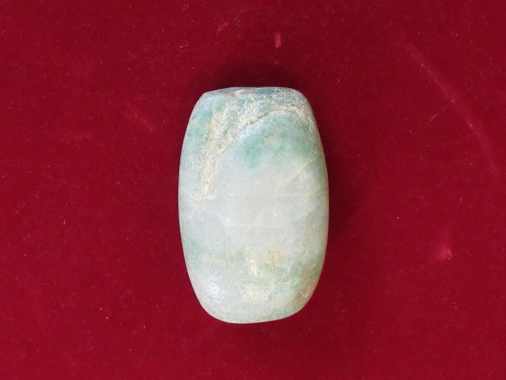 滑らかな楕円形で、白色に淡い緑色が混ざり合った翡翠大珠の写真