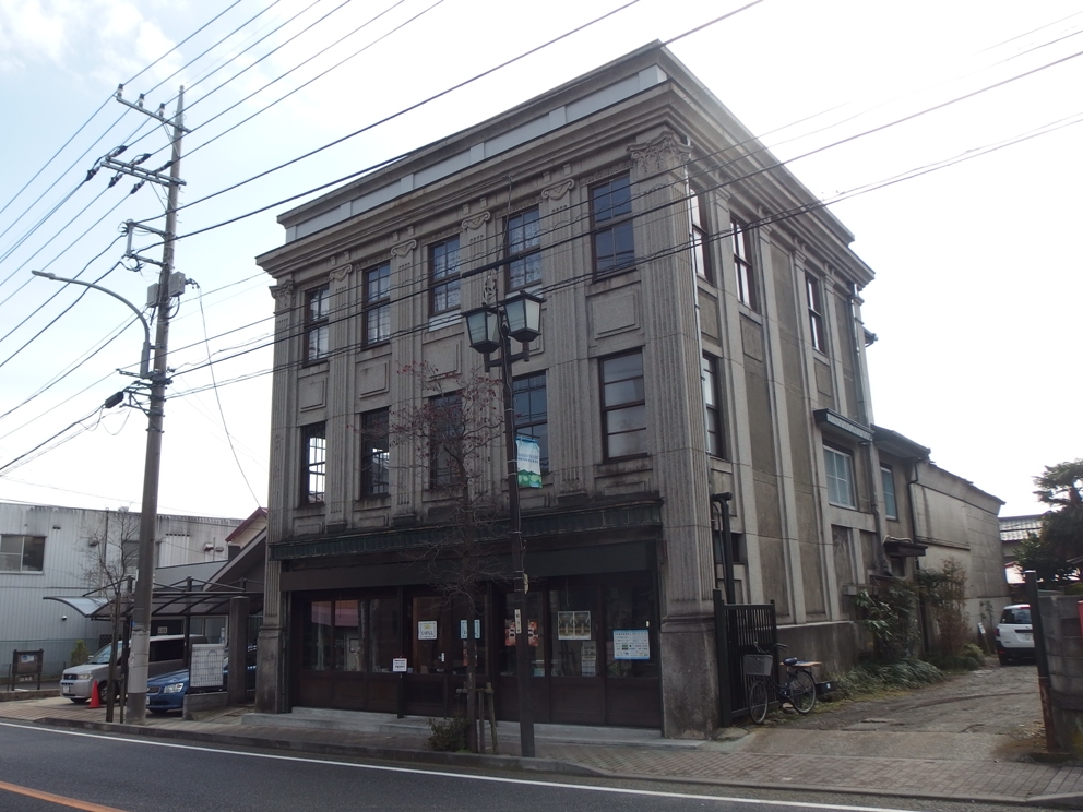 道路沿いの電線や電柱の間に建っている石造りのような重厚な造りの古いビルを写した写真