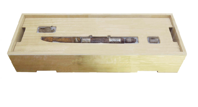 長方形の木箱の中に、銀色の装飾が施された、茶色くさびた刀が収められている銀装圭頭大刀の写真                                 刀剣のようなものが収められており、他の小さな断片も一緒に展示されている写真銀装圭頭大刀