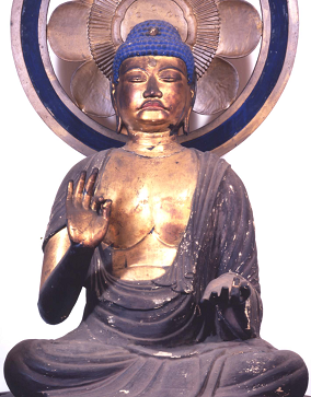 光背を頂き、顔や体が金色に塗られ、座禅を組んで片手を上げ、もう一方の手を膝に置いている阿弥陀如来坐像の写真