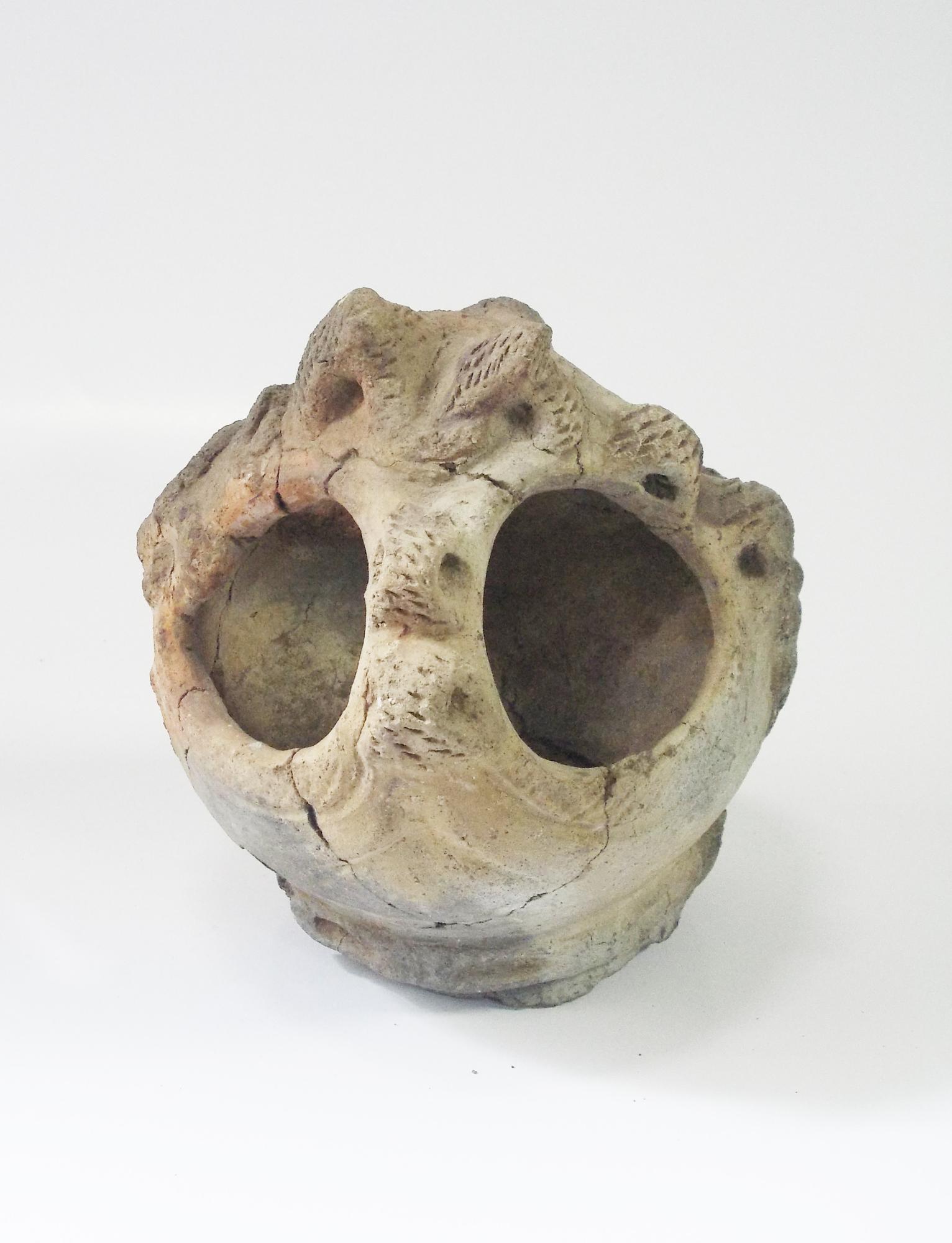 上部に二つの大きな穴が開いており、表面には縄目のような模様が施された土器の写真