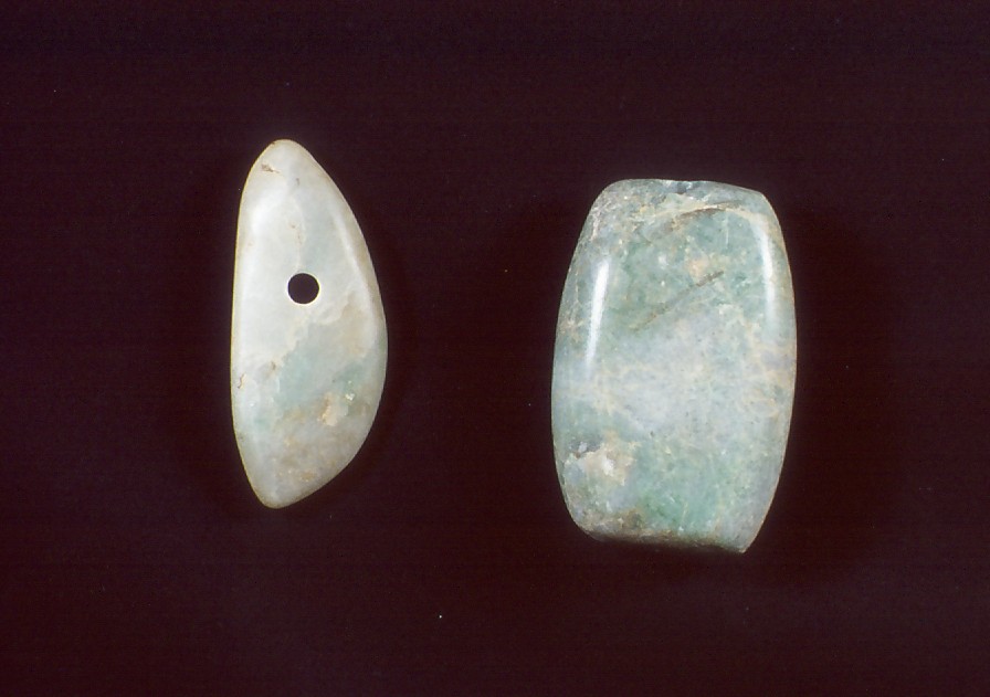 左に楕円形で上部に穴が空いた薄い緑色と白が混ざった翡翠大珠、右に丸みを帯びた長方形で薄い緑色の翡翠大珠が二つ並んでいる写真