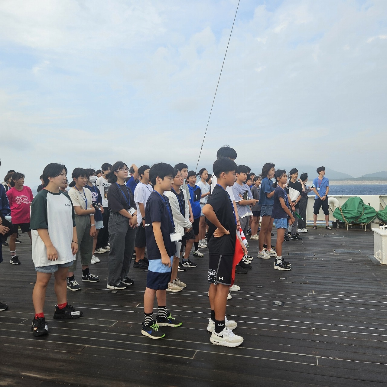 大勢の子どもたちが船のデッキに整列している朝のつどいの様子の写真