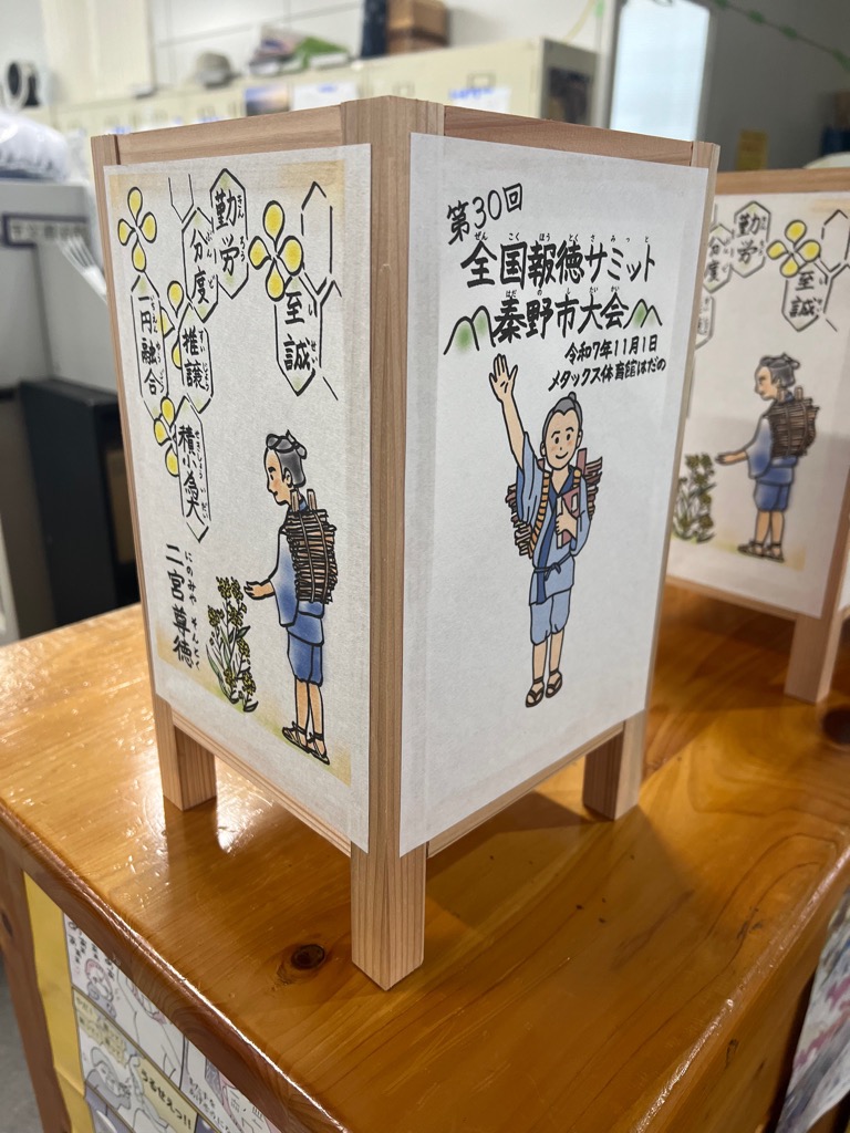 二宮金次郎のイラストや「全国報徳サミット秦野市大会」の文字が書かれた白い紙が、木の枠に貼られたあんどんの写真