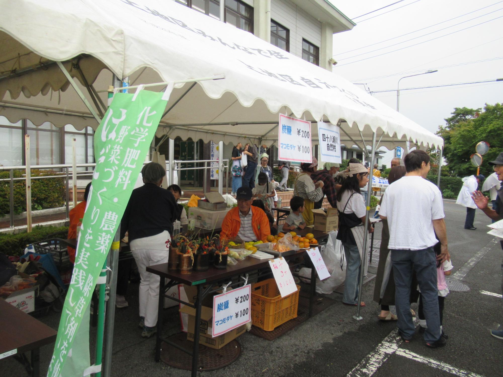 白いテントの下に置いたテーブルに商品が並び、周りは多くの来場者で賑わっている様子の写真