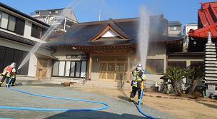 消防士たちが、寺院の建物の屋根に向かって放水訓練をしている様子を捉えた、消火活動訓練の写真