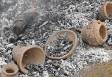燃えて白くなった炭や灰の上に、焼成された鉢形や壷型の土器が複数ある様子の写真