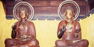 後光を背に、蓮華座に座り、右手を上げた二体の木造仏像が安置され、右側の木造仏像は左手で衣服の端を握っている写真