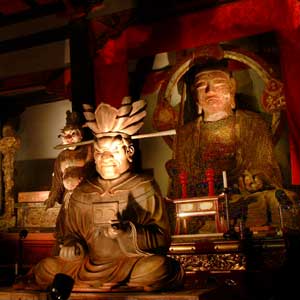 うす暗い部屋で、複数の仏像が安置され、ライトで照らされており、手前には怒りの面相の座像がある木造十王像等諸仏の写真