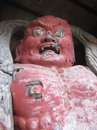 口を大きく開け、憤怒の表情をしており、全身が赤く塗られた筋肉質な阿形（あぎょう）像の胸から上の写真