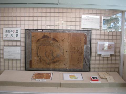 壁に額に入った大きな古地図や資料が展示され、その前に置かれた台に複数の資料が並んでいる、柳川村砂降絵図の展示の様子の写真